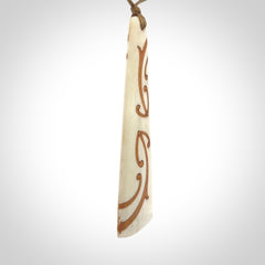 A hand carved, double sided, bone toki with triple koru, intricate pendant. The cord is a camel colour and is adjustable.