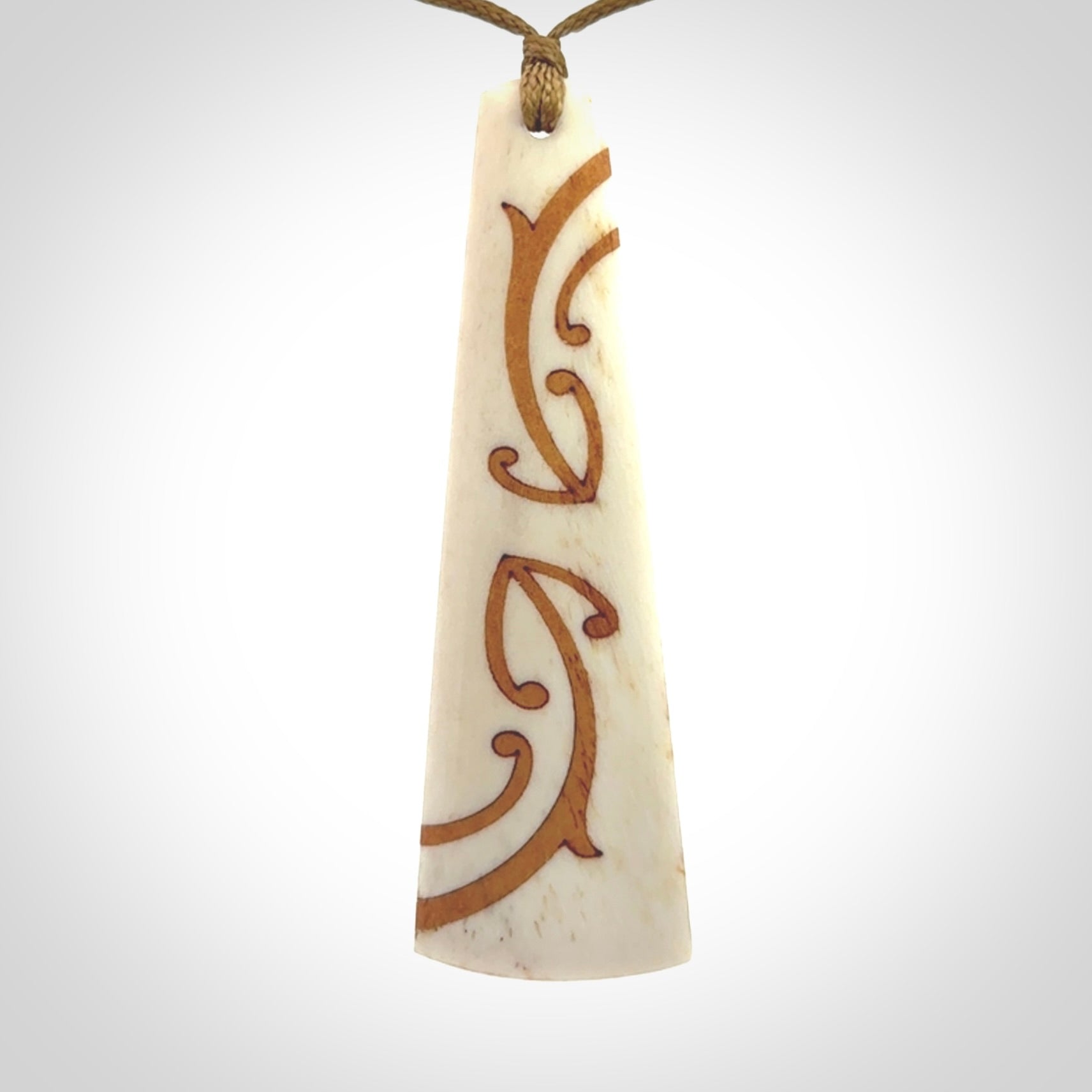 A hand carved, double sided, bone toki with triple koru, intricate pendant. The cord is a camel colour and is adjustable.