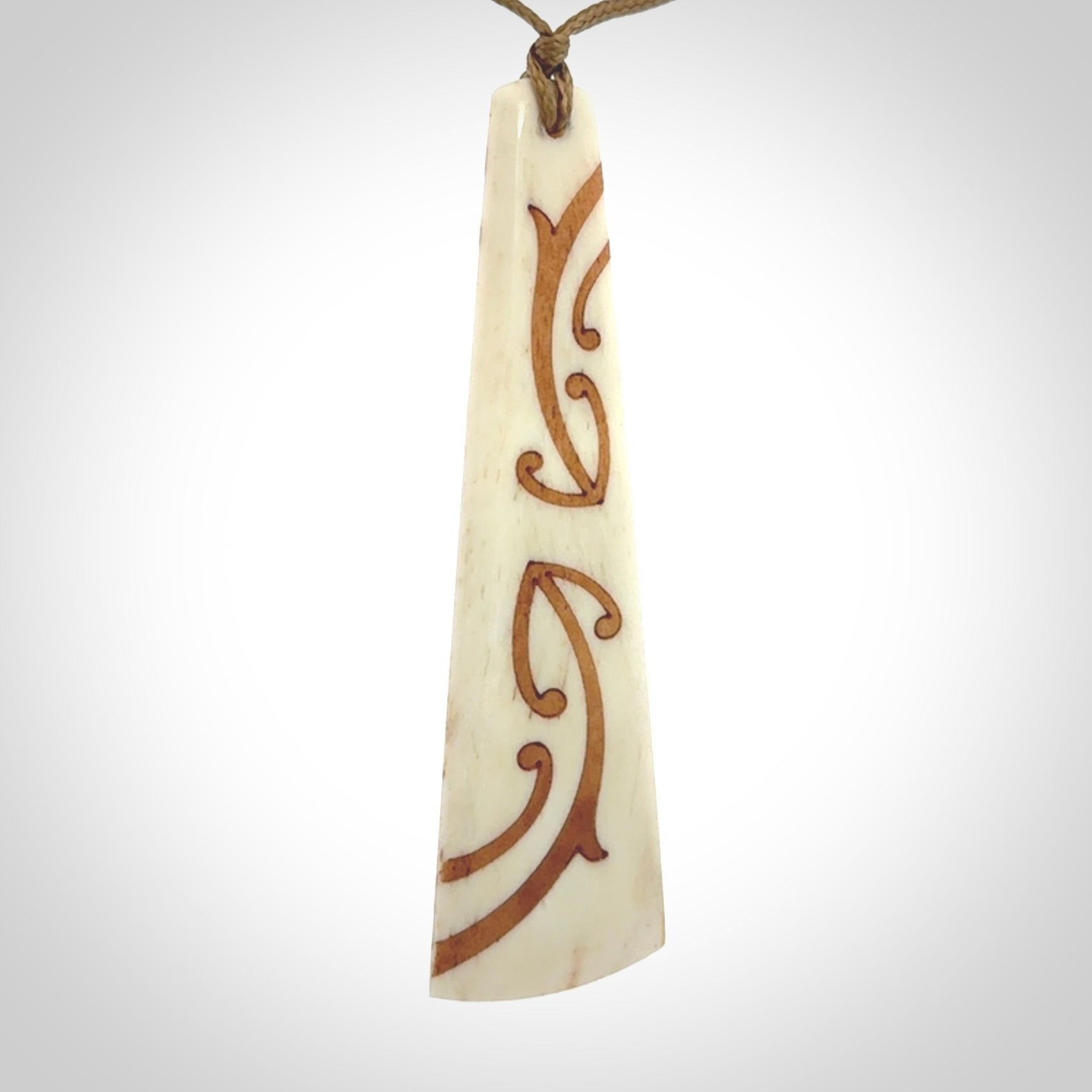 A hand carved, double sided, bone toki with triple koru, intricate pendant. The cord is a camel colour and is adjustable.