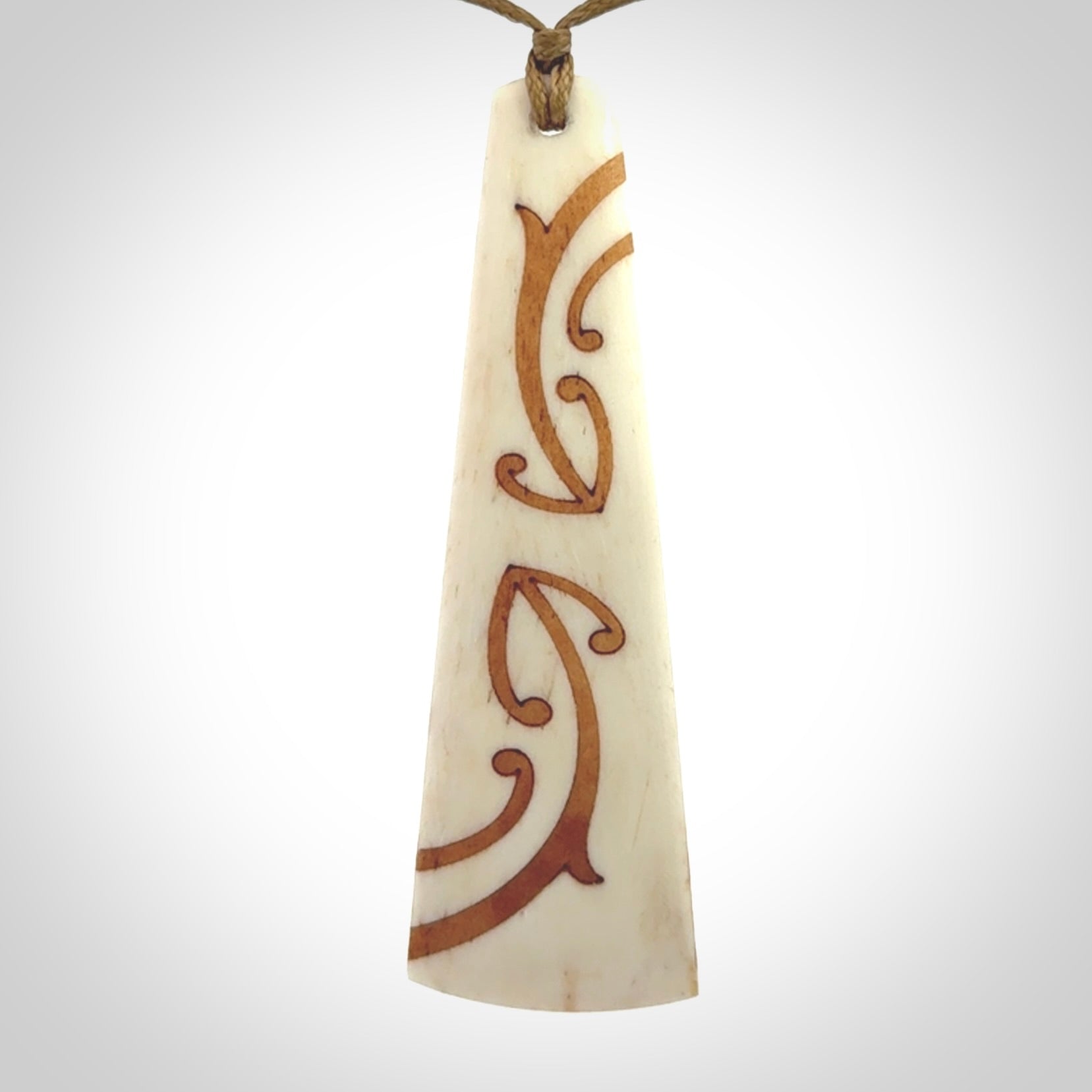 A hand carved, double sided, bone toki with triple koru, intricate pendant. The cord is a camel colour and is adjustable.
