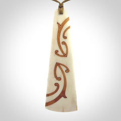 A hand carved, double sided, bone toki with triple koru, intricate pendant. The cord is a camel colour and is adjustable.
