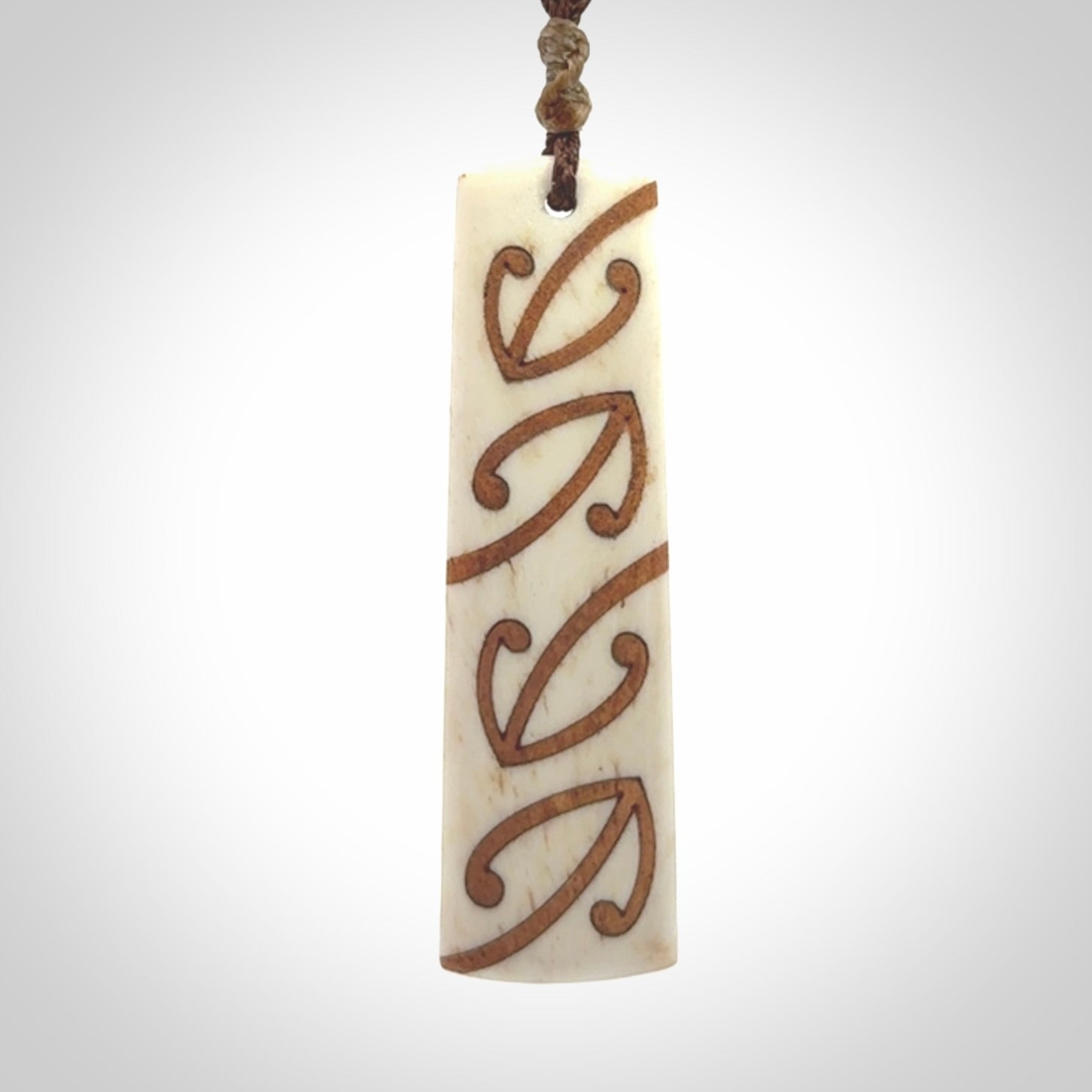 A hand carved, double sided, bone toki with triple koru, intricate pendant. The cord is a brown colour and is adjustable.
