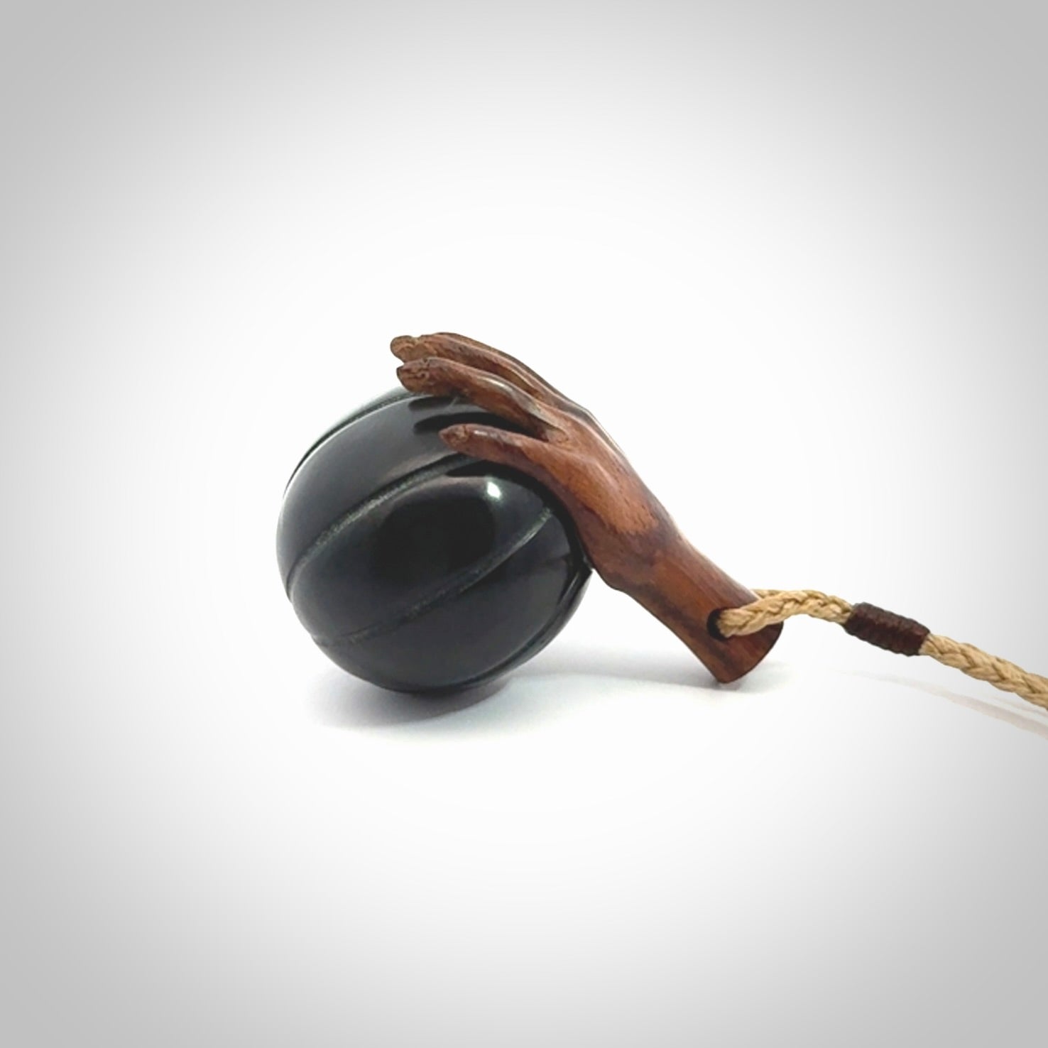 This is a very cool pendant that we've had carved for all you Basketball fans. This is a pendant with a wooden hand holding a black jade basketball. We provide this on an adjustable cord, and we ship worldwide
