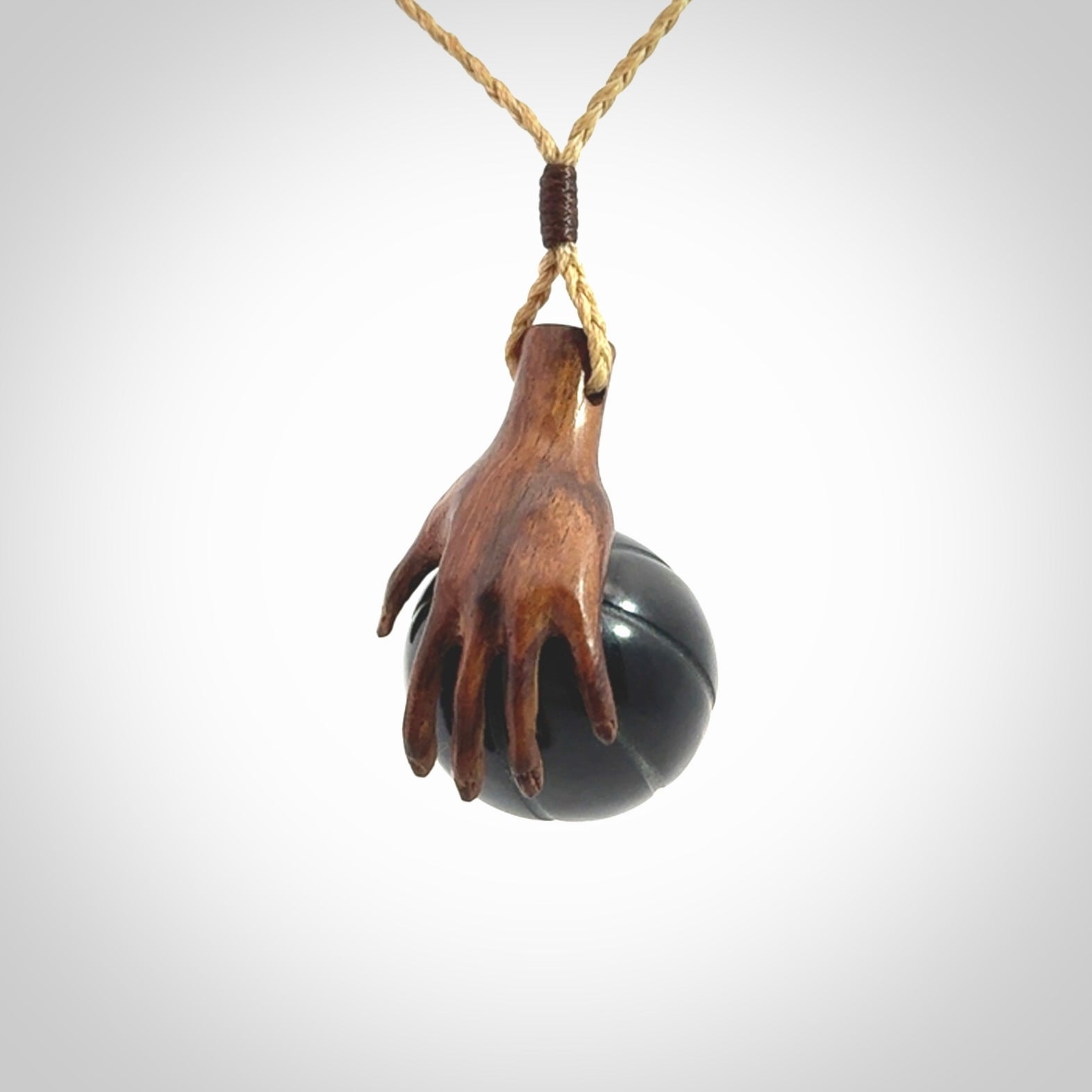 This is a very cool pendant that we've had carved for all you Basketball fans. This is a pendant with a wooden hand holding a black jade basketball. We provide this on an adjustable cord, and we ship worldwide