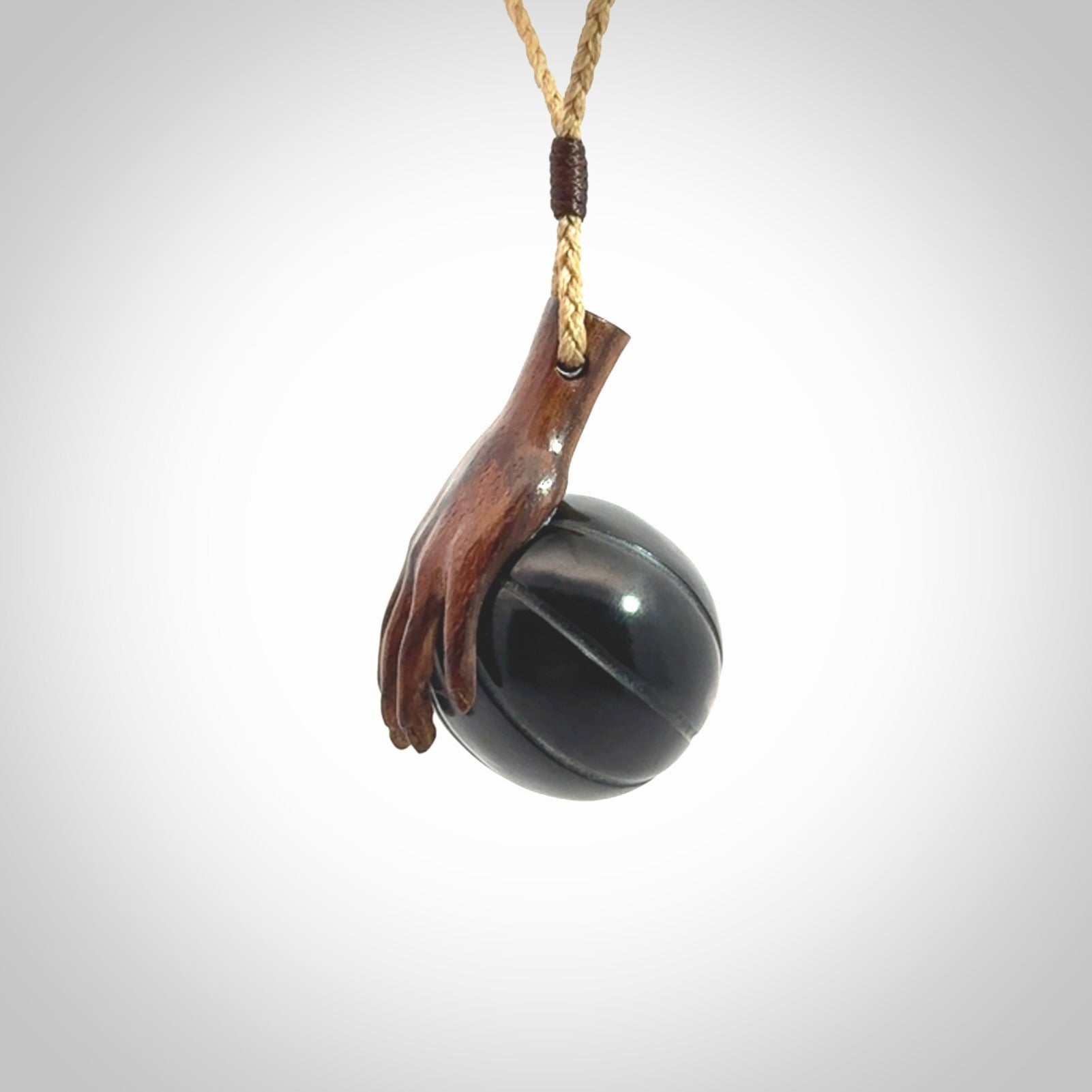 This is a very cool pendant that we've had carved for all you Basketball fans. This is a pendant with a wooden hand holding a black jade basketball. We provide this on an adjustable cord, and we ship worldwide
