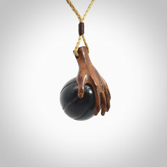 This is a very cool pendant that we've had carved for all you Basketball fans. This is a pendant with a wooden hand holding a black jade basketball. We provide this on an adjustable cord, and we ship worldwide