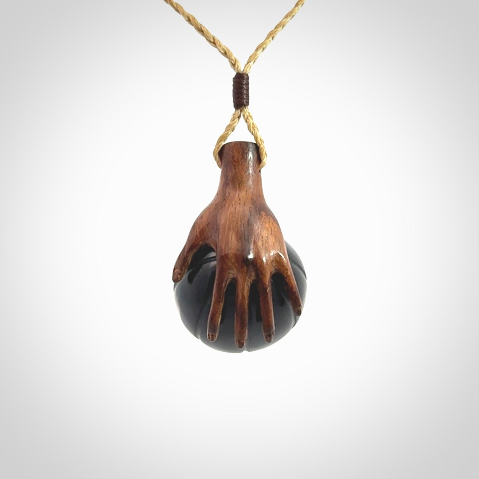 This is a very cool pendant that we've had carved for all you Basketball fans. This is a pendant with a wooden hand holding a black jade basketball. We provide this on an adjustable cord, and we ship worldwide