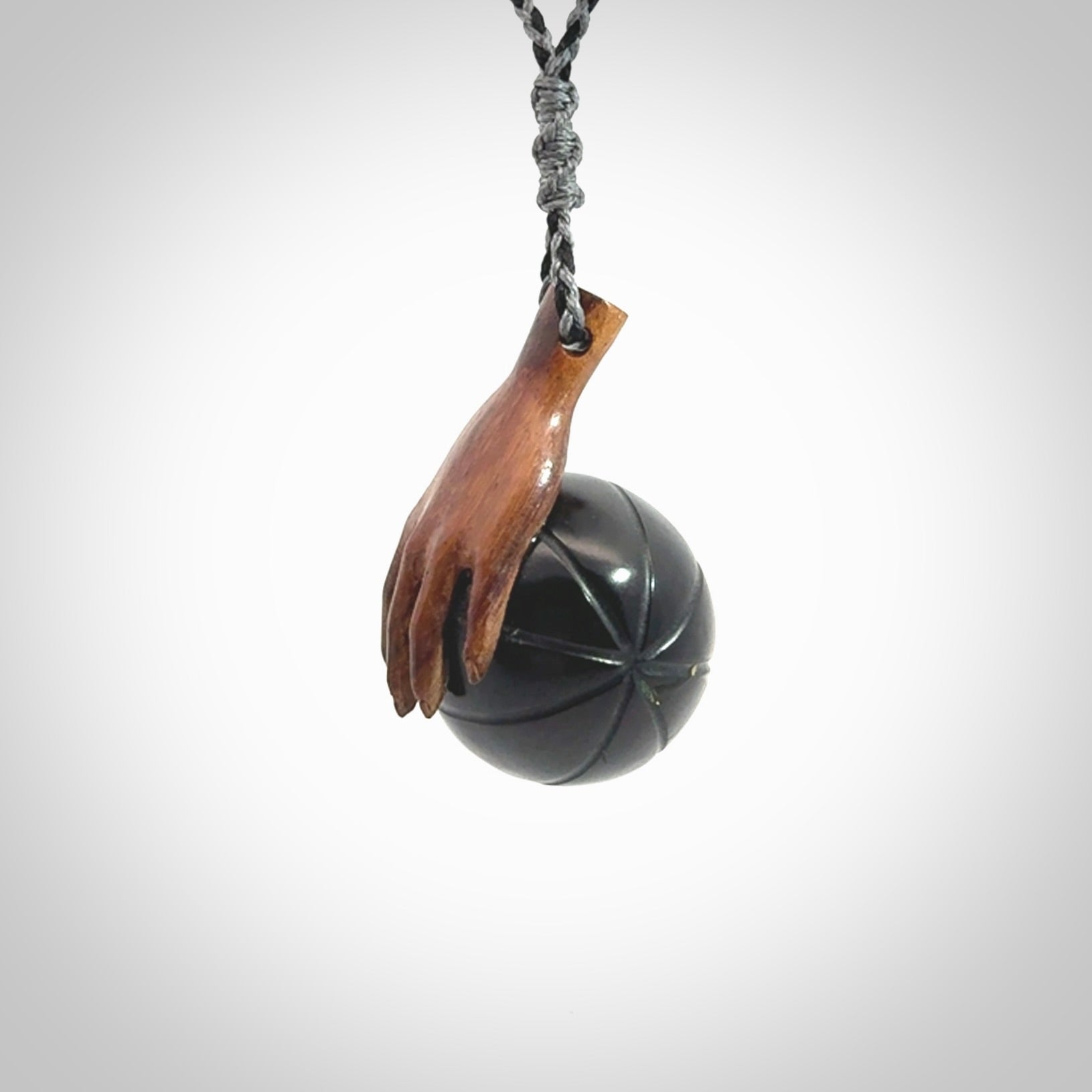 This is a very cool pendant that we've had carved for all you Basketball fans. This is a pendant with a wooden hand holding a black jade basketball. We provide this on an adjustable cord, and we ship worldwide