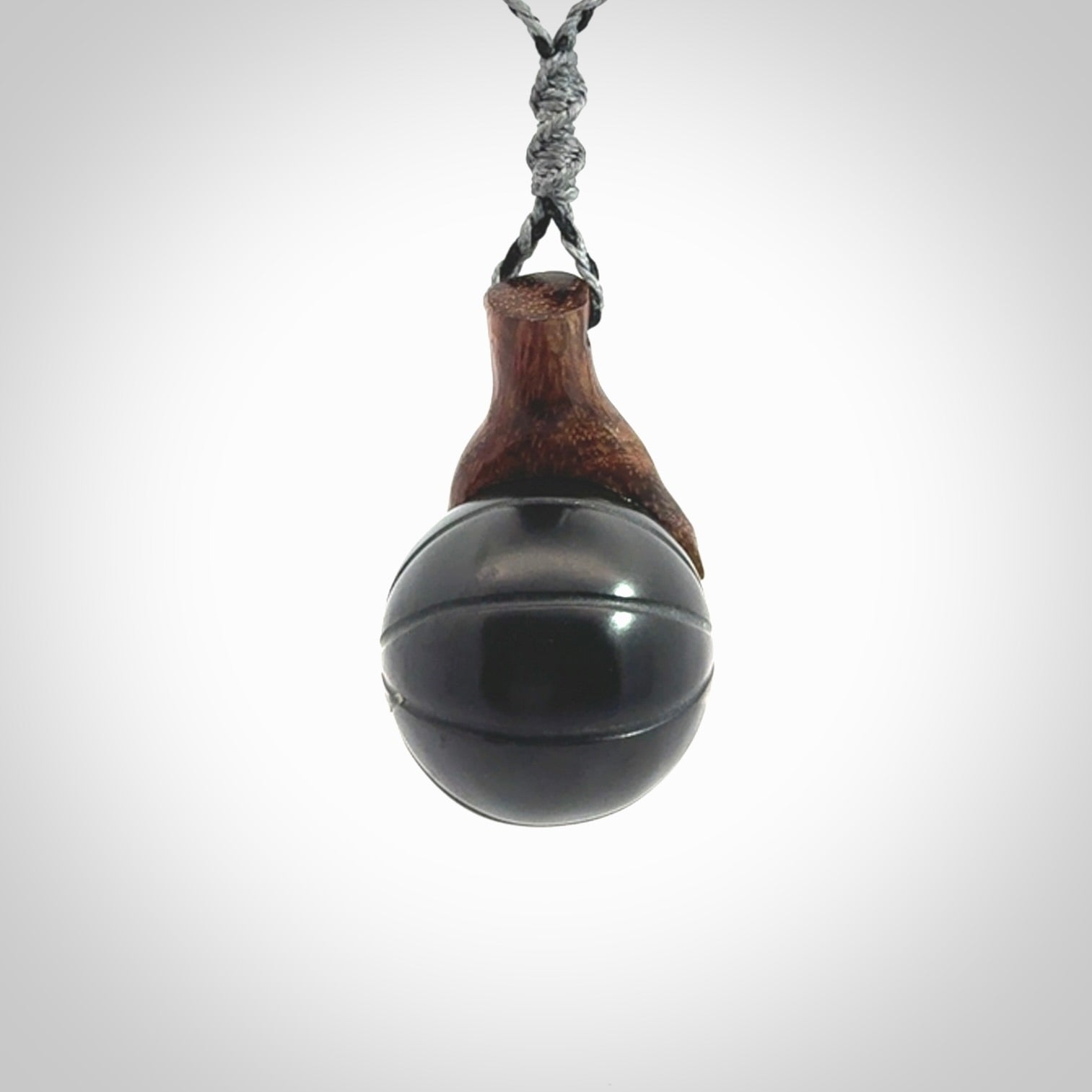 This is a very cool pendant that we've had carved for all you Basketball fans. This is a pendant with a wooden hand holding a black jade basketball. We provide this on an adjustable cord, and we ship worldwide
