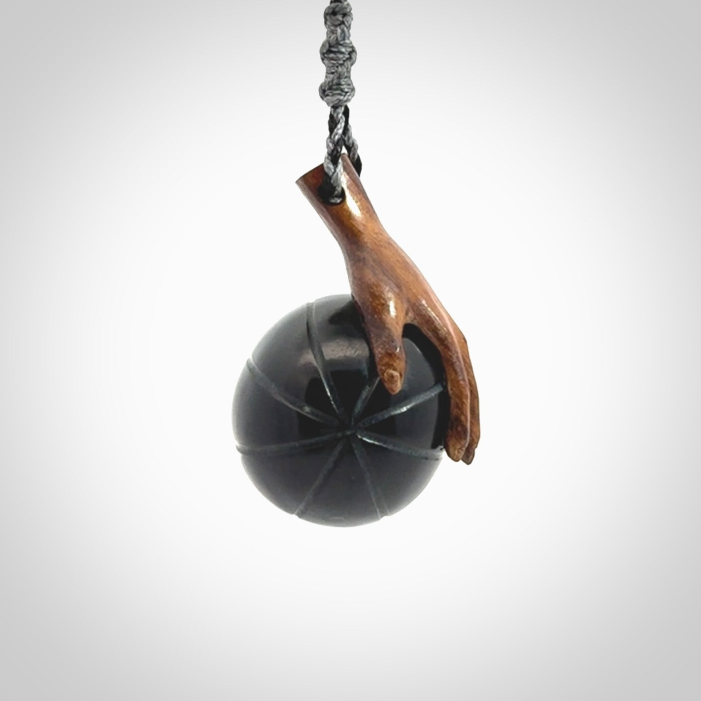 This is a very cool pendant that we've had carved for all you Basketball fans. This is a pendant with a wooden hand holding a black jade basketball. We provide this on an adjustable cord, and we ship worldwide