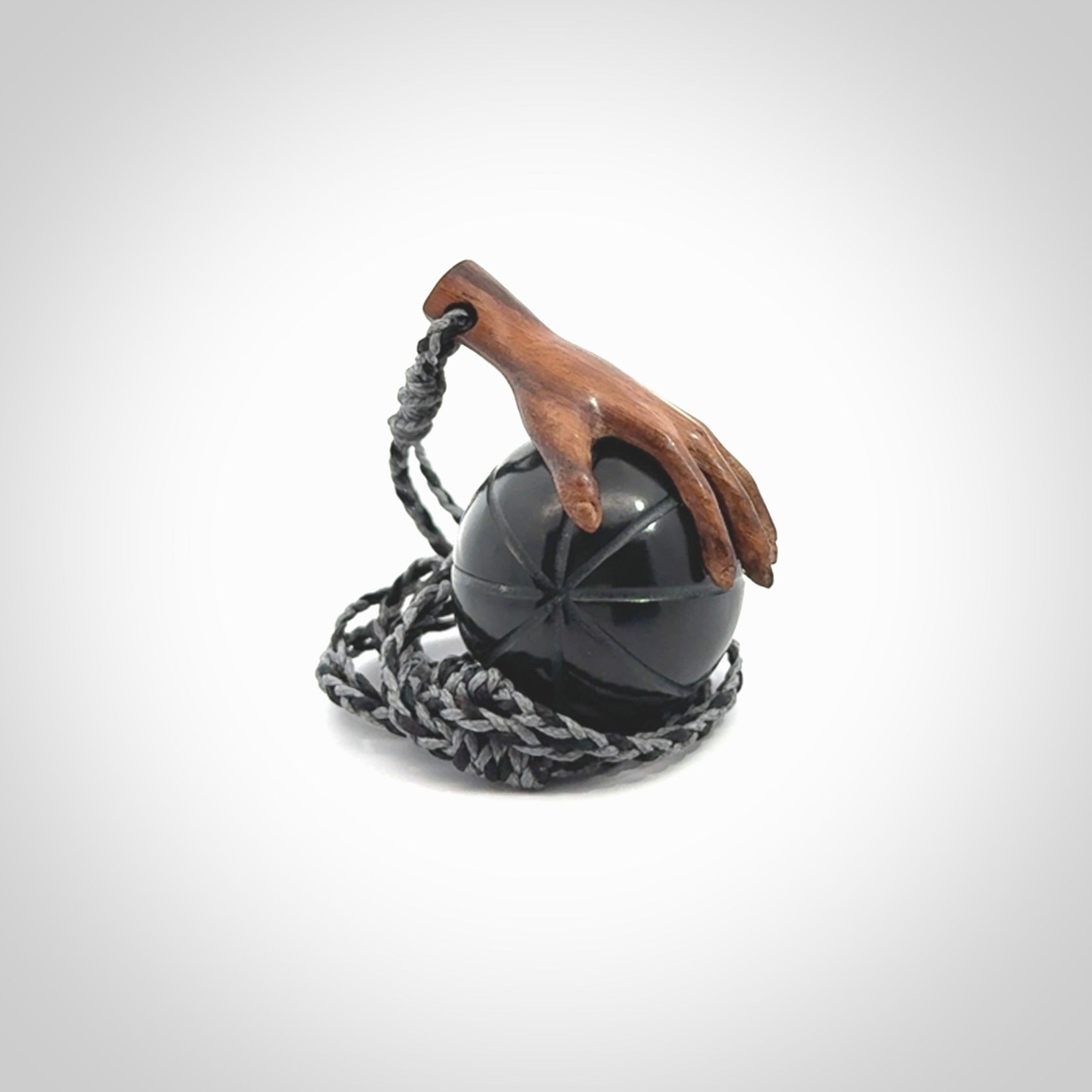 This is a very cool pendant that we've had carved for all you Basketball fans. This is a pendant with a wooden hand holding a black jade basketball. We provide this on an adjustable cord, and we ship worldwide