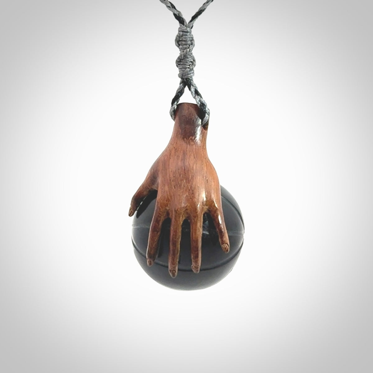 This is a very cool pendant that we've had carved for all you Basketball fans. This is a pendant with a wooden hand holding a black jade basketball. We provide this on an adjustable cord, and we ship worldwide