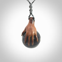 This is a very cool pendant that we've had carved for all you Basketball fans. This is a pendant with a wooden hand holding a black jade basketball. We provide this on an adjustable cord, and we ship worldwide