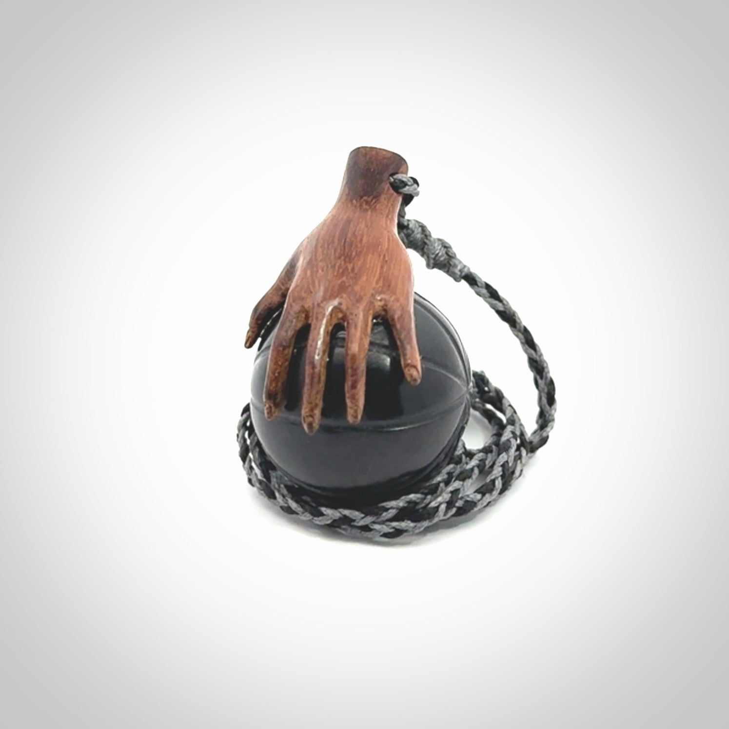 This is a very cool pendant that we've had carved for all you Basketball fans. This is a pendant with a wooden hand holding a black jade basketball. We provide this on an adjustable cord, and we ship worldwide