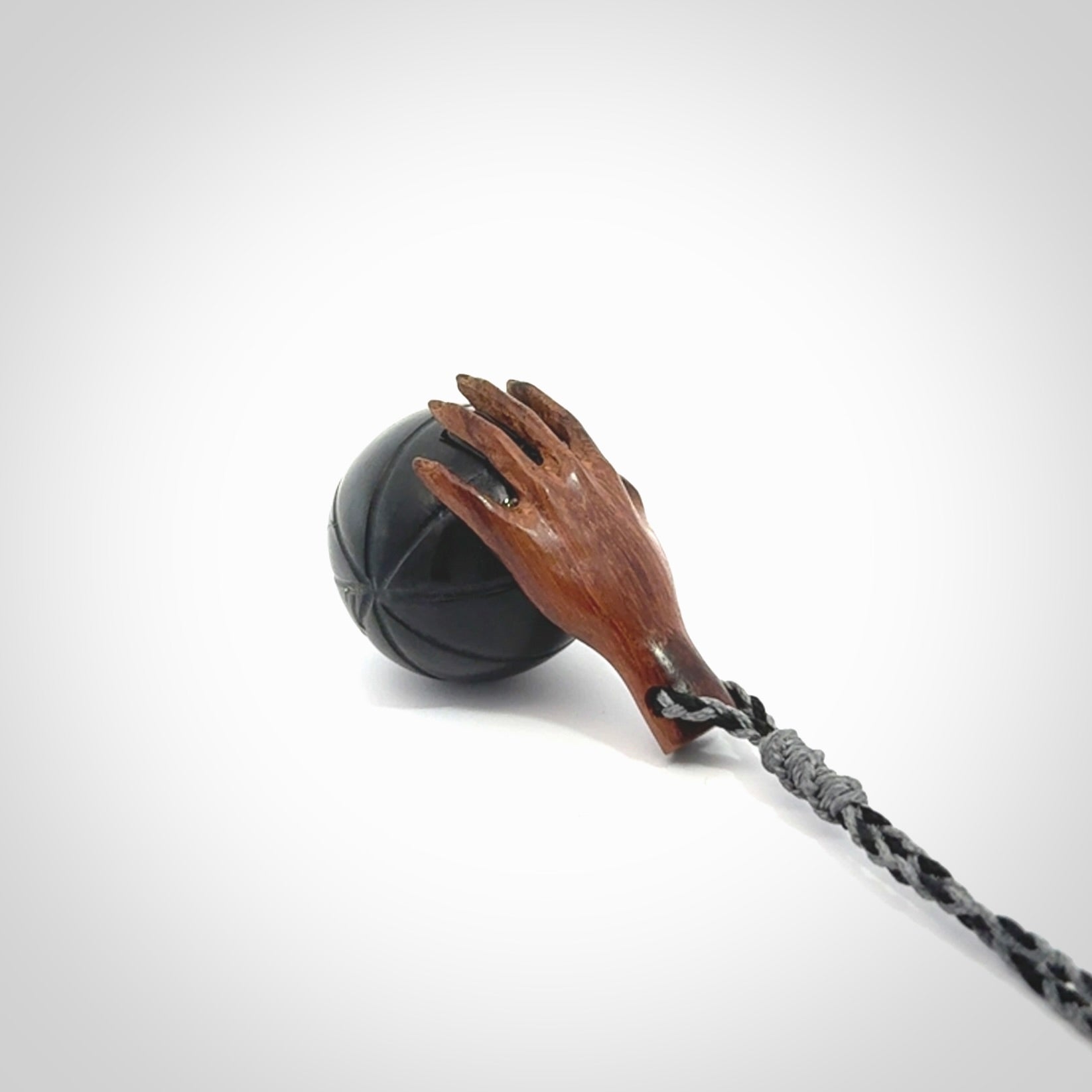 This is a very cool pendant that we've had carved for all you Basketball fans. This is a pendant with a wooden hand holding a black jade basketball. We provide this on an adjustable cord, and we ship worldwide