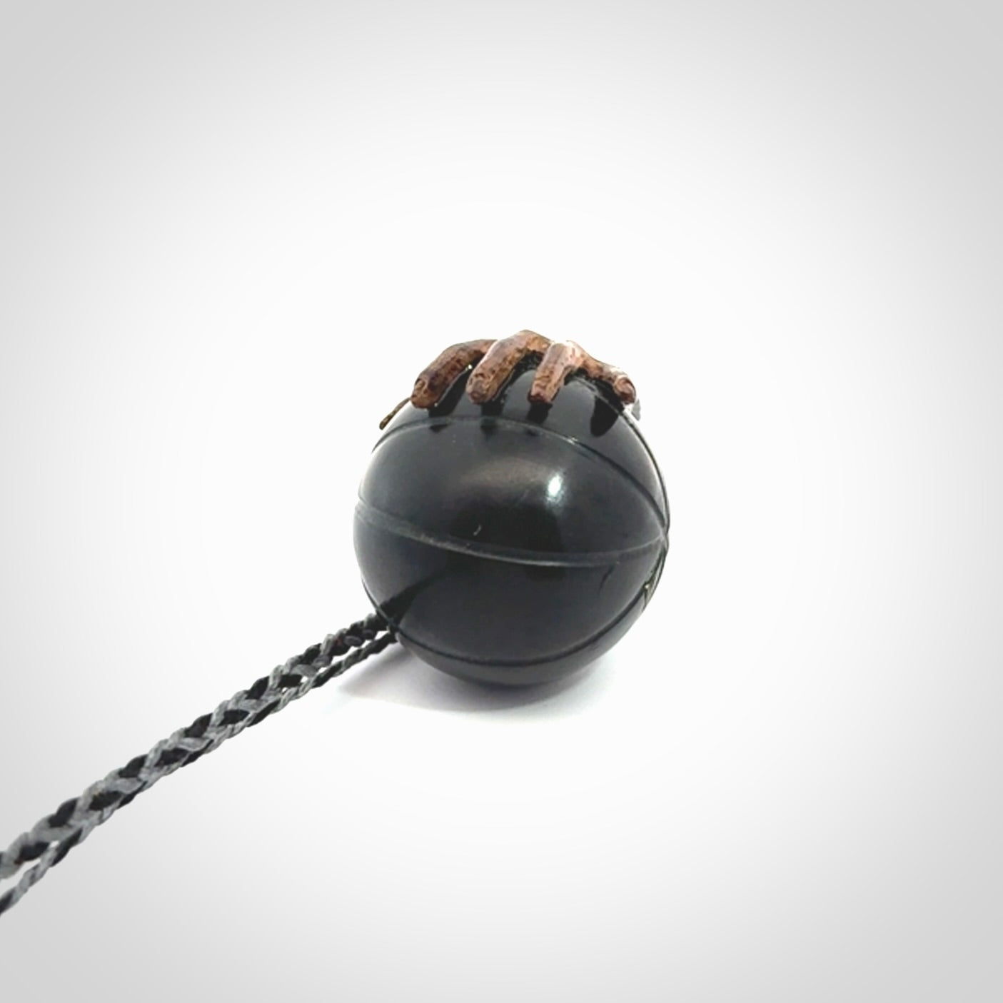 This is a very cool pendant that we've had carved for all you Basketball fans. This is a pendant with a wooden hand holding a black jade basketball. We provide this on an adjustable cord, and we ship worldwide