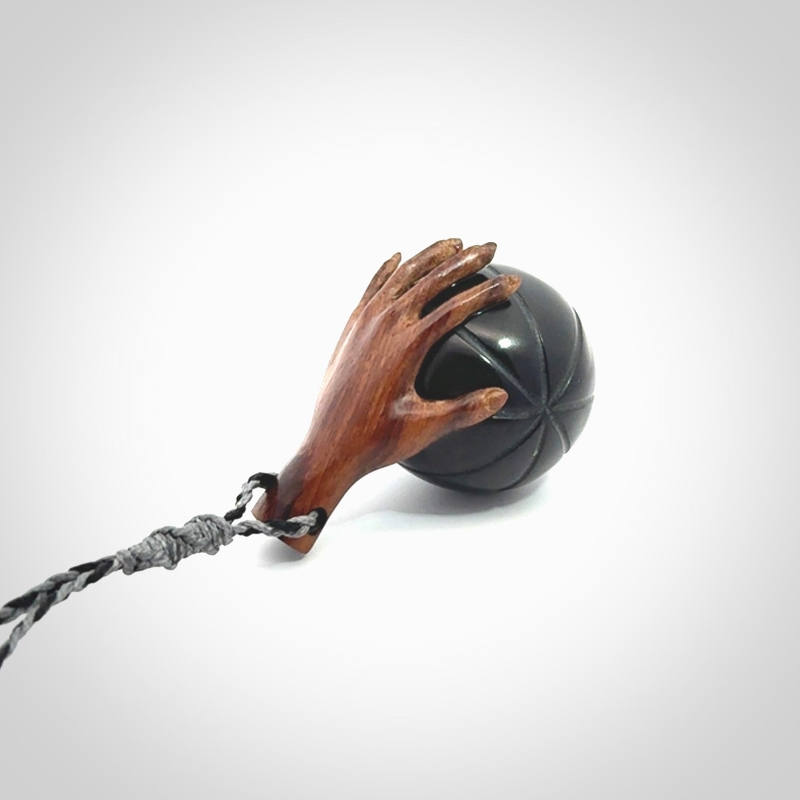 This is a very cool pendant that we've had carved for all you Basketball fans. This is a pendant with a wooden hand holding a black jade basketball. We provide this on an adjustable cord, and we ship worldwide