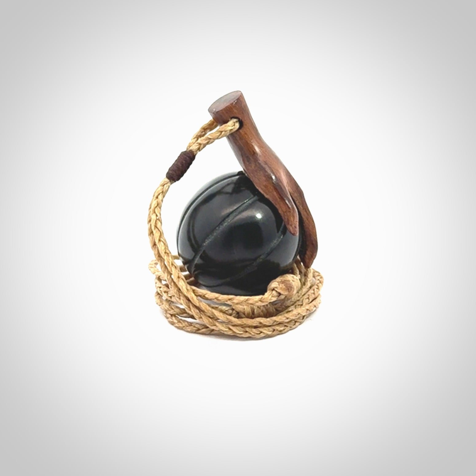 This is a very cool pendant that we've had carved for all you Basketball fans. This is a pendant with a wooden hand holding a black jade basketball. We provide this on an adjustable cord, and we ship worldwide