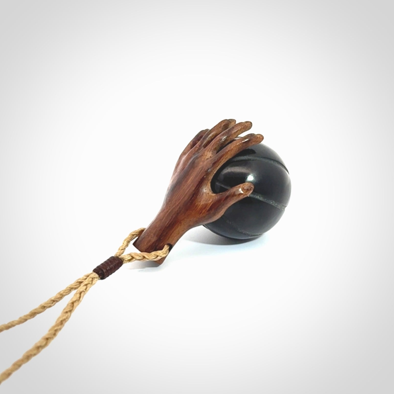 This is a very cool pendant that we've had carved for all you Basketball fans. This is a pendant with a wooden hand holding a black jade basketball. We provide this on an adjustable cord, and we ship worldwide