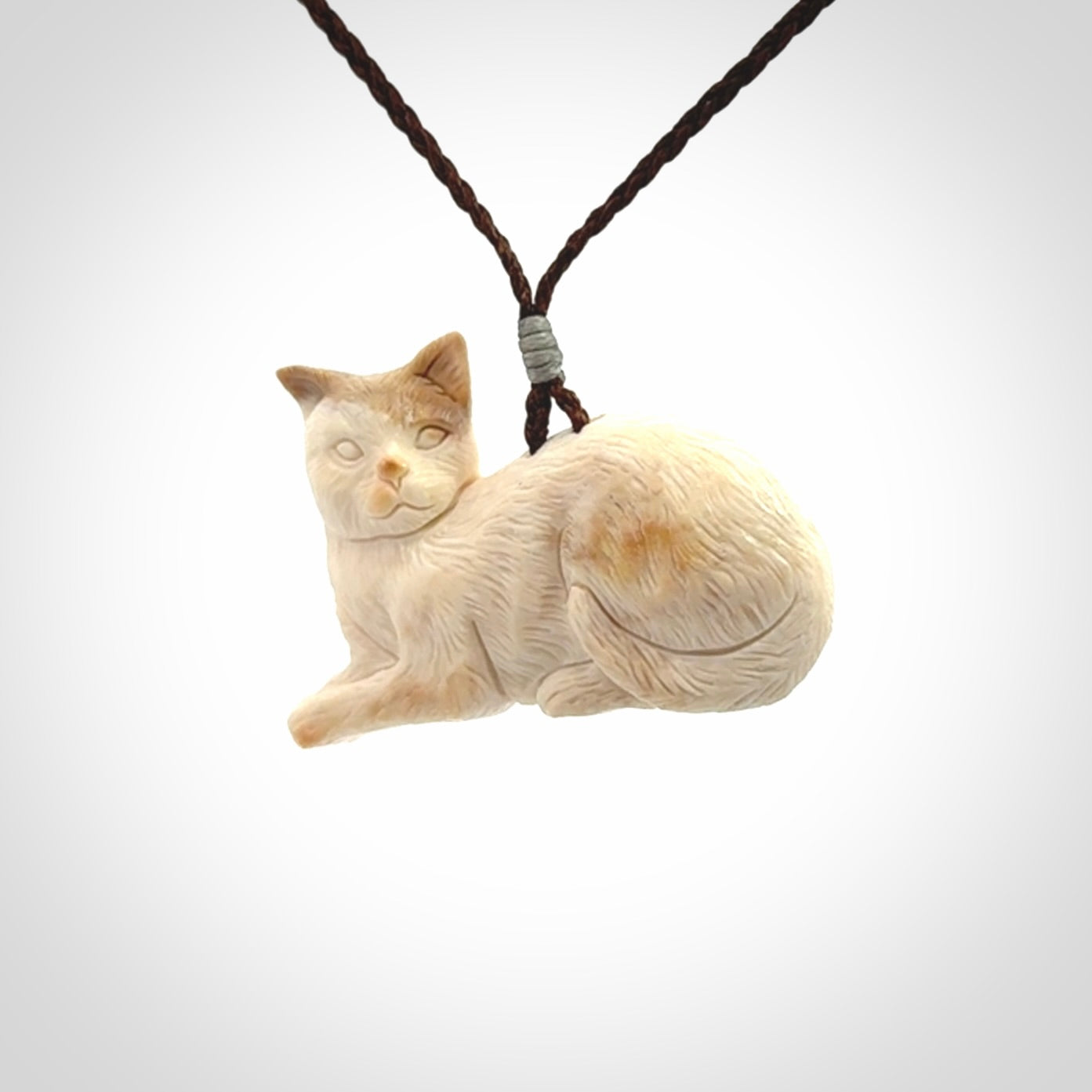 This cat pendant radiates quiet elegance with a regal composure. Hand made in bone.