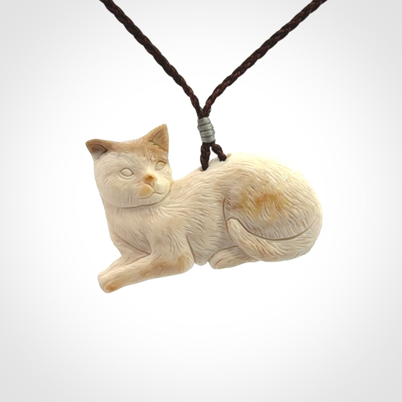 This cat pendant radiates quiet elegance with a regal composure. Hand made in bone.