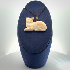 This cat pendant radiates quiet elegance with a regal composure. Hand made in bone.