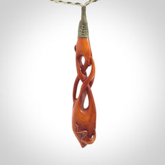 This pendant is carved from cow bone and stained with a homemade tea dye. It is a unique piece of wearable art that is sure to catch the eye. The shape is a complex twist form and has been beautifully hand carved by bone carver Yuri Terenyi.