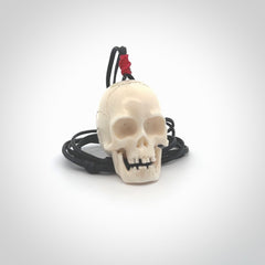 This picture shows a large sized Deer Antler Bone skull pendant that we have hand carved. It is polished to a soft shine and is a very striking piece. The cord is black and has a small red floret binding just above the pendant.