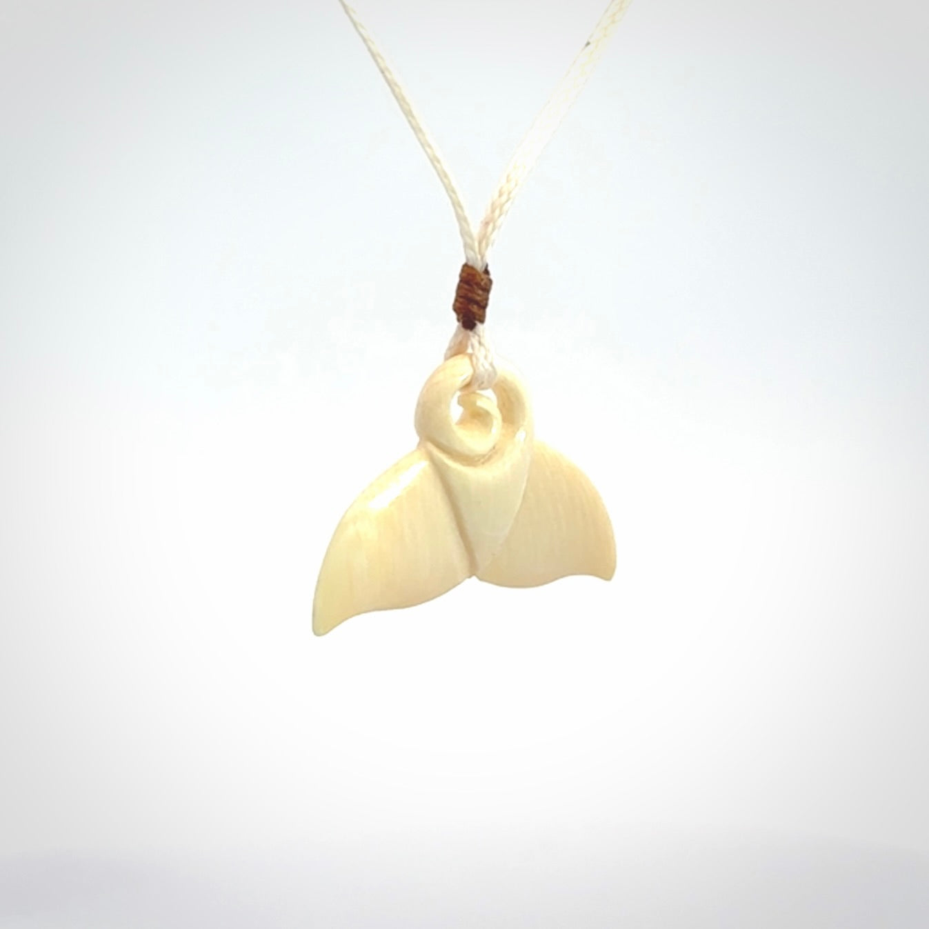 This photo shows a small whaletail pendant that we have carved from a light honey coloured piece of Woolly Mammoth tusk. It is suspended on a an adjustable cord.