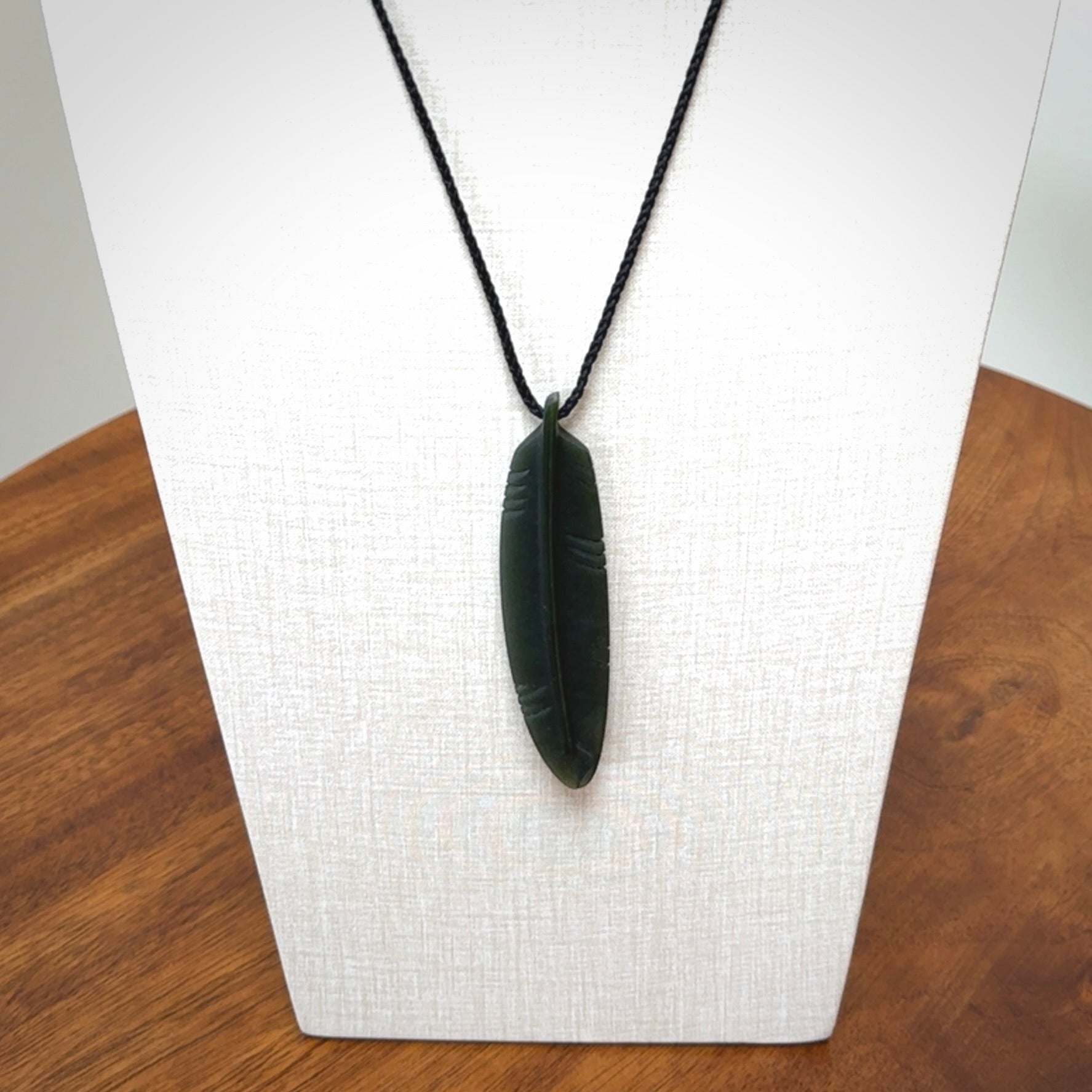 A hand carved large New Zealand Jade feather necklace. The cord is a black colour and is a fixed length. A large sized hand made Jade feather necklace by New Zealand artist Kerry Thompson. One off work of art to wear.