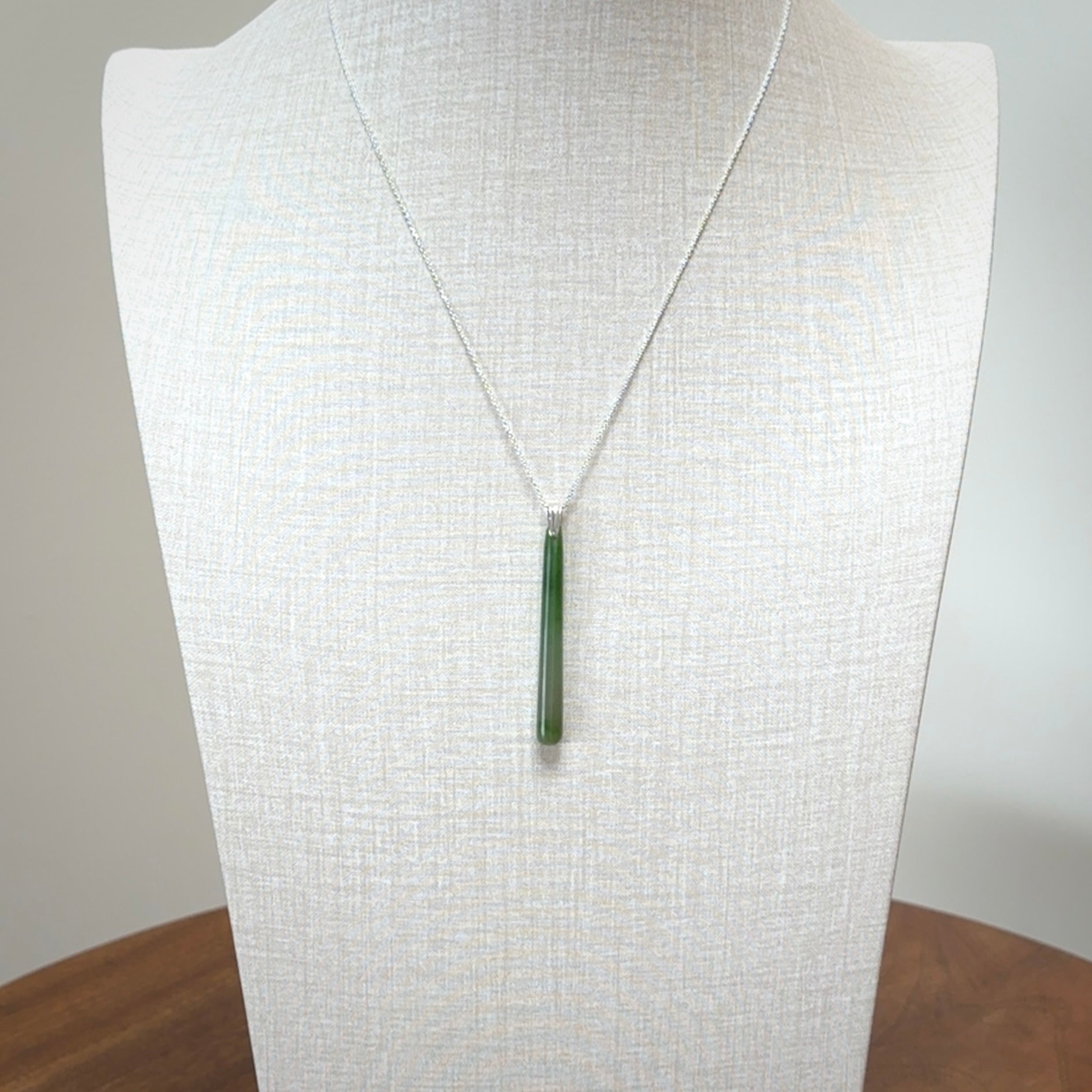 A hand carved New Zealand Jade Drop pendant with sterling silver clasp and chain.