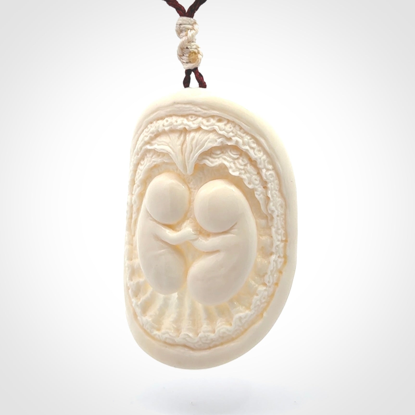 This is a contemporary large pendant carved in bone. Hand carved and provided with an adjustable cord. Twins in womb pendant.