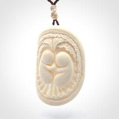 This is a contemporary large pendant carved in bone. Hand carved and provided with an adjustable cord. Twins in womb pendant.
