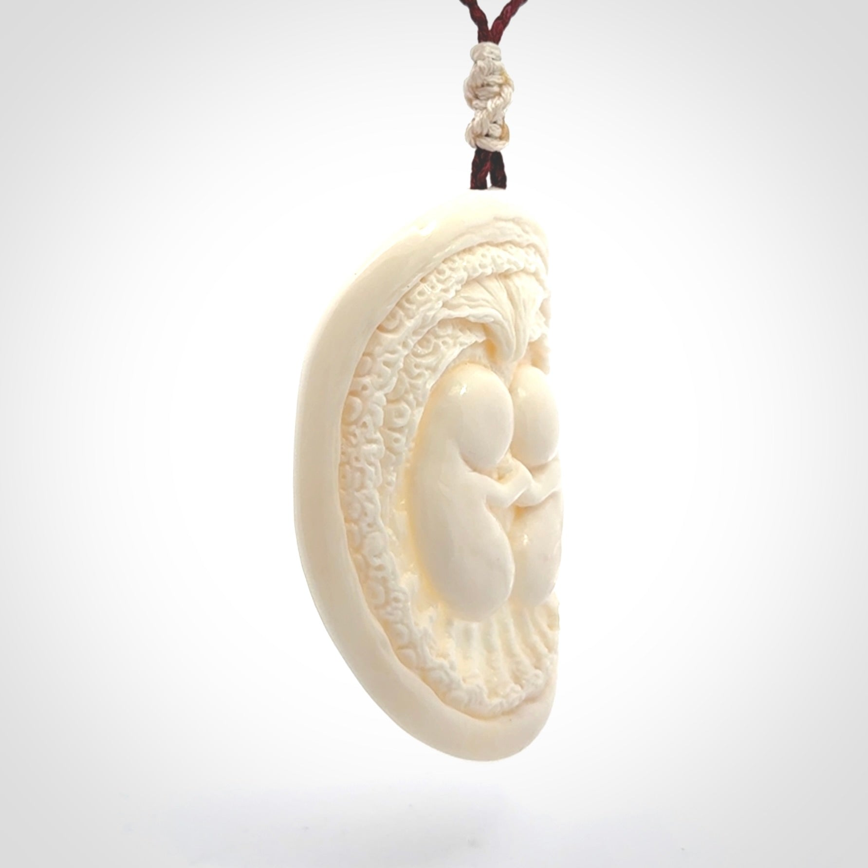 This is a contemporary large pendant carved in bone. Hand carved and provided with an adjustable cord. Twins in womb pendant.