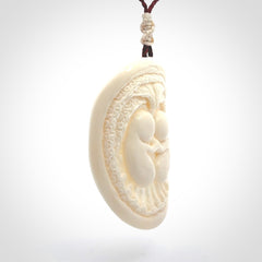 This is a contemporary large pendant carved in bone. Hand carved and provided with an adjustable cord. Twins in womb pendant.