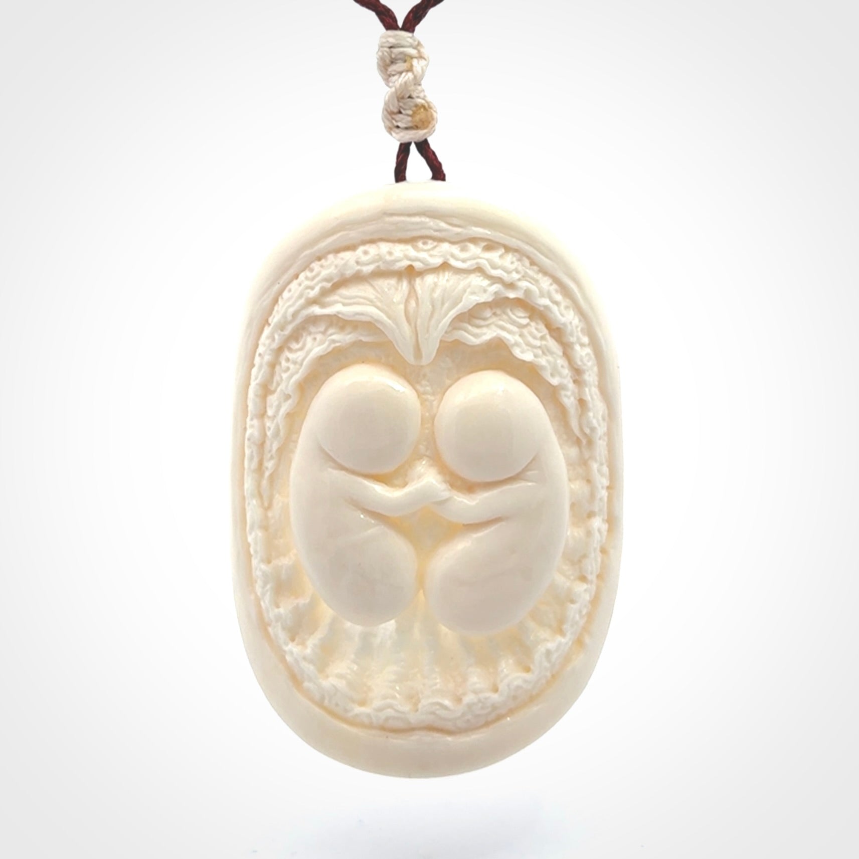 This is a contemporary large pendant carved in bone. Hand carved and provided with an adjustable cord. Twins in womb pendant.