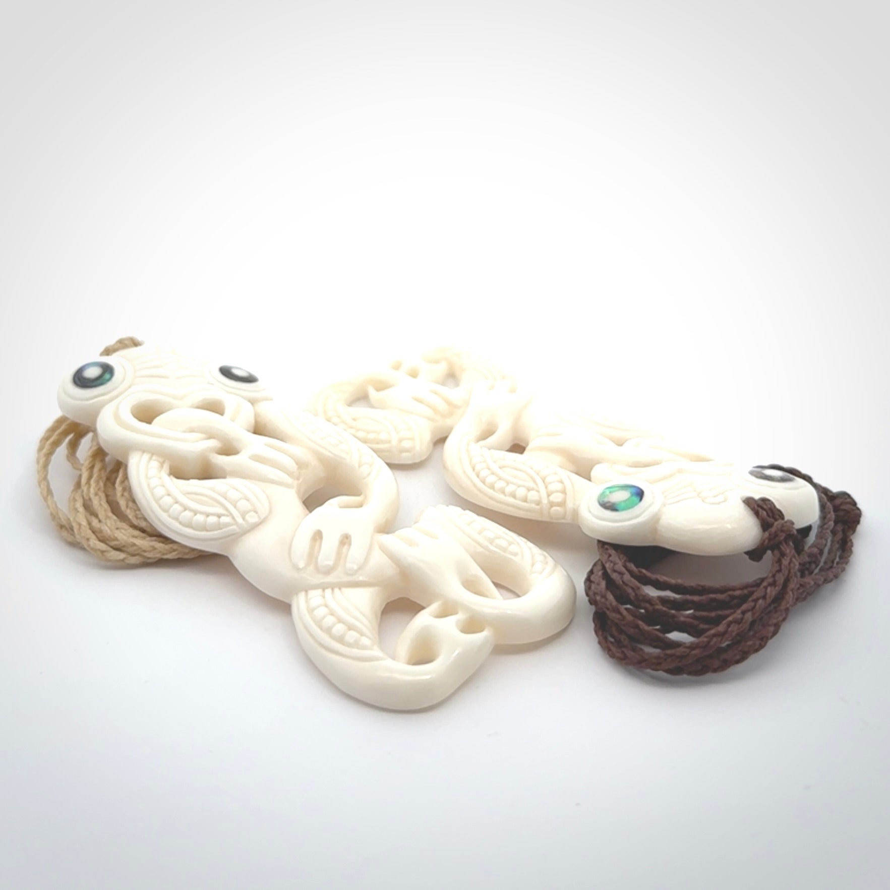 Hand carved bone Tiki pendant. Traditional art hand carved for NZ Pacific. Bone Tiki necklace with Paua Shell eyes. Delivered with Express Courier. Provided with adjustable cords and packaged in a woven kete pouch.