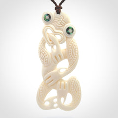 Hand carved bone Tiki pendant. Traditional art hand carved for NZ Pacific. Bone Tiki necklace with Paua Shell eyes. Delivered with Express Courier. Provided with adjustable cords and packaged in a woven kete pouch.