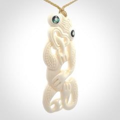 Hand carved bone Tiki pendant. Traditional art hand carved for NZ Pacific. Bone Tiki necklace with Paua Shell eyes. Delivered with Express Courier. Provided with adjustable cords and packaged in a woven kete pouch.