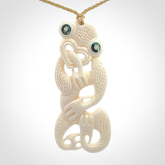 Hand carved bone Tiki pendant. Traditional art hand carved for NZ Pacific. Bone Tiki necklace with Paua Shell eyes. Delivered with Express Courier. Provided with adjustable cords and packaged in a woven kete pouch.