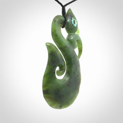 This picture shows a large traditional manaia pendant carved in New Zealand Jade with Paua shell eyes.