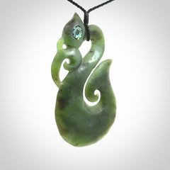 This picture shows a large traditional manaia pendant carved in New Zealand Jade with Paua shell eyes.