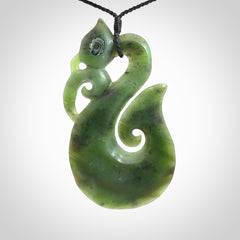 This picture shows a large traditional manaia pendant carved in New Zealand Jade with Paua shell eyes.
