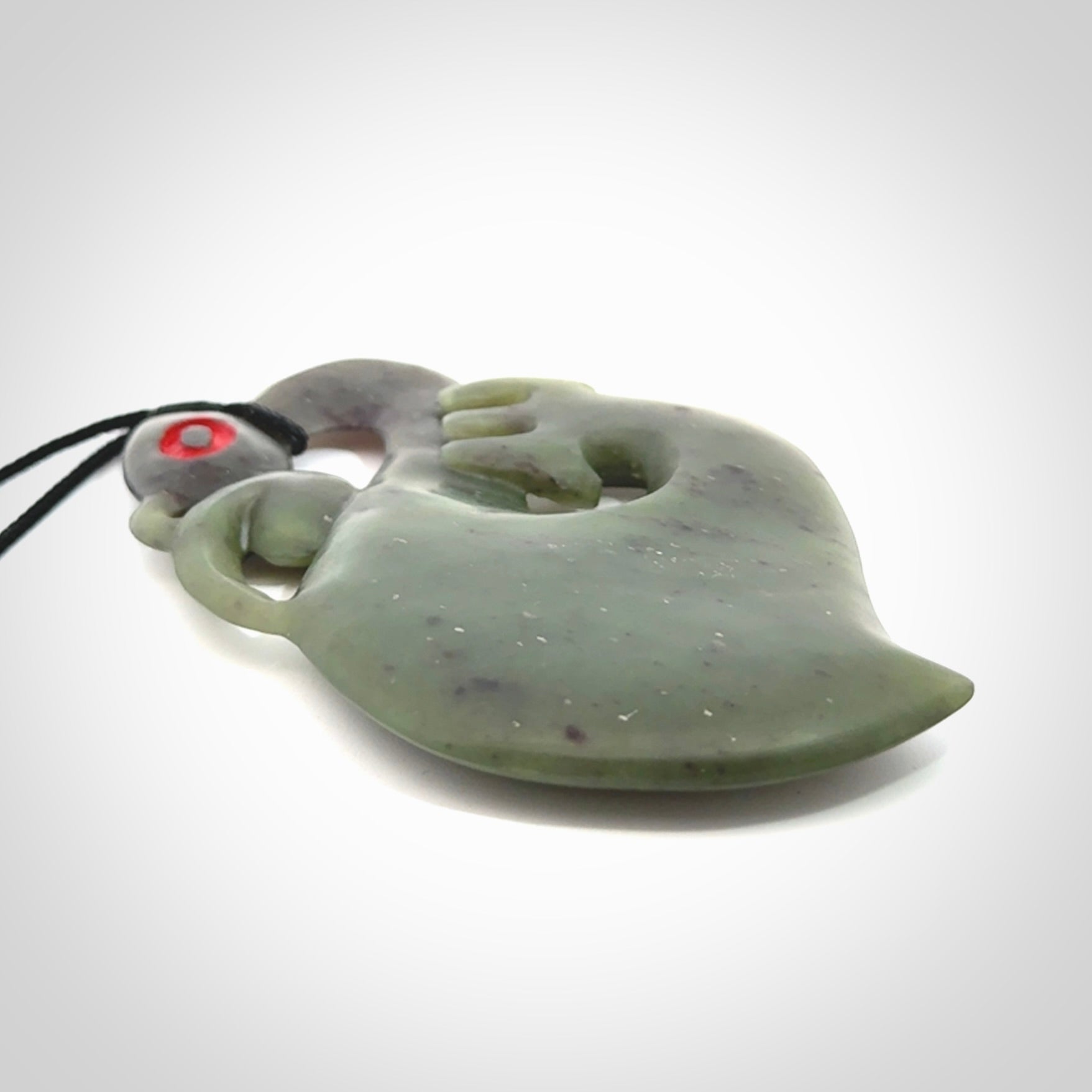 This picture shows a large traditional manaia pendant carved in New Zealand Jade.