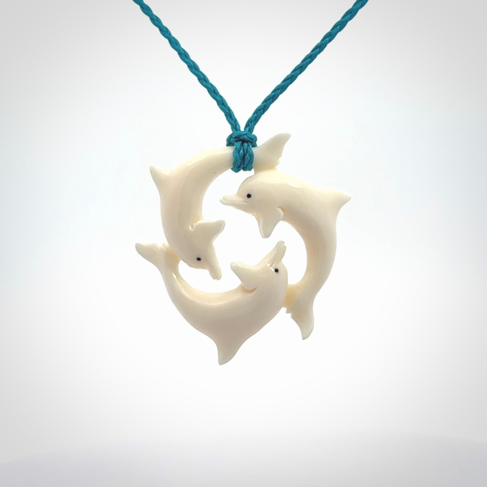Hand carved dolphin trio pendant, made from natural bone by NZ Pacific. Hand made natural bone dolphin trilogy necklace, provided with an adjustable cord