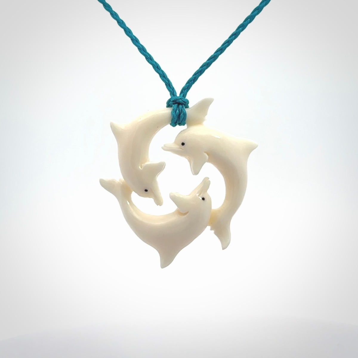 Hand carved dolphin trio pendant, made from natural bone by NZ Pacific. Hand made natural bone dolphin trilogy necklace, provided with an adjustable cord