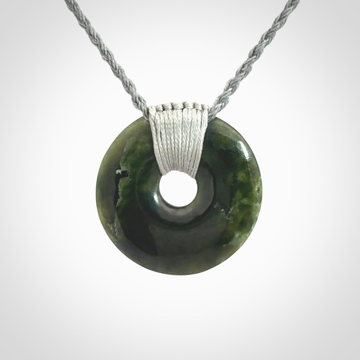 These are medium sized pendants - very finely carved. They are New Zealand Jade discs with a centre hole. It is suspended from a cord which is adjustable. These are beautiful pieces of expressive jade jewellery. Unique New Zealand made pendants for men and women. Perfect gifts for all.