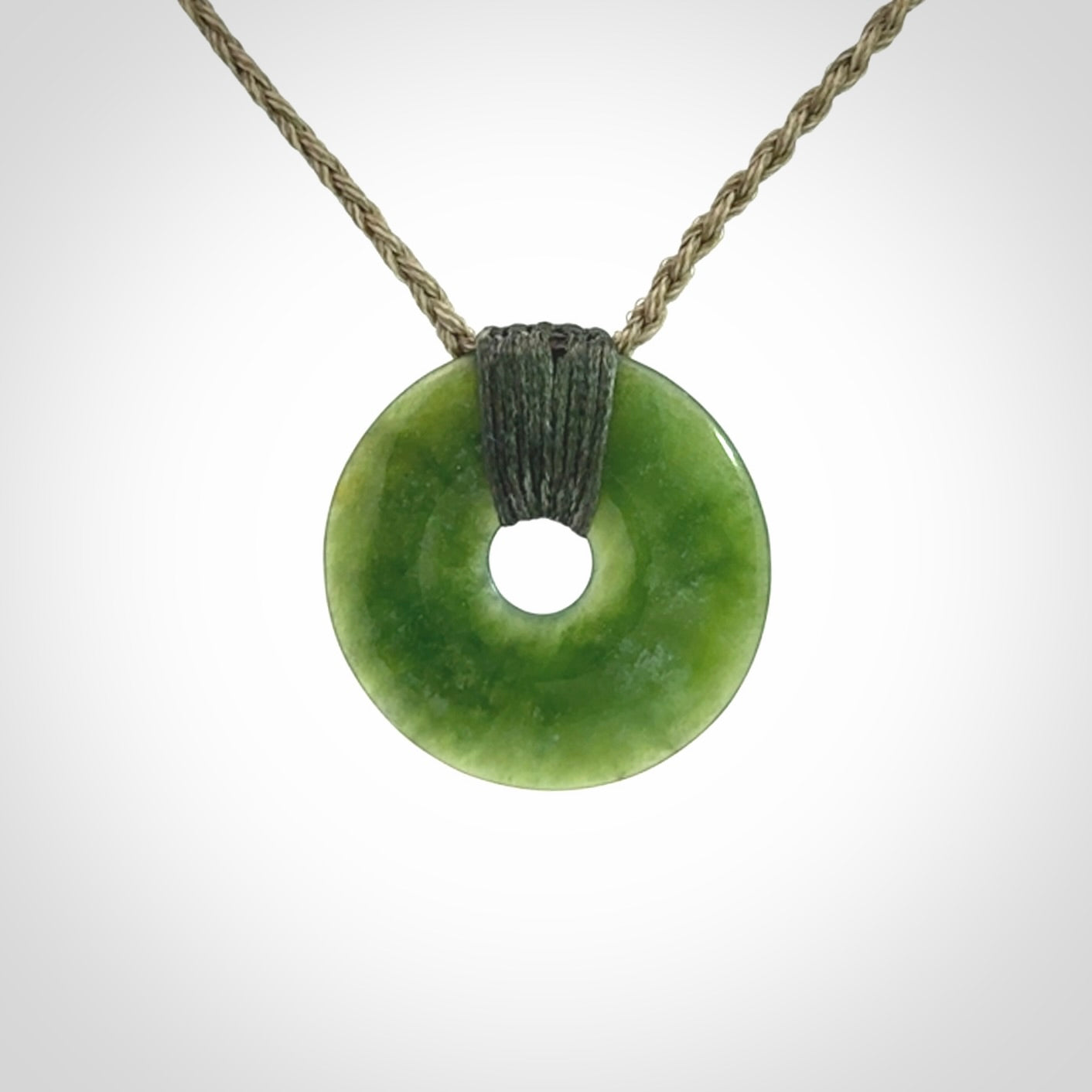 These are medium sized pendants - very finely carved. They are New Zealand Jade discs with a centre hole. It is suspended from a cord which is adjustable. These are beautiful pieces of expressive jade jewellery. Unique New Zealand made pendants for men and women. Perfect gifts for all.