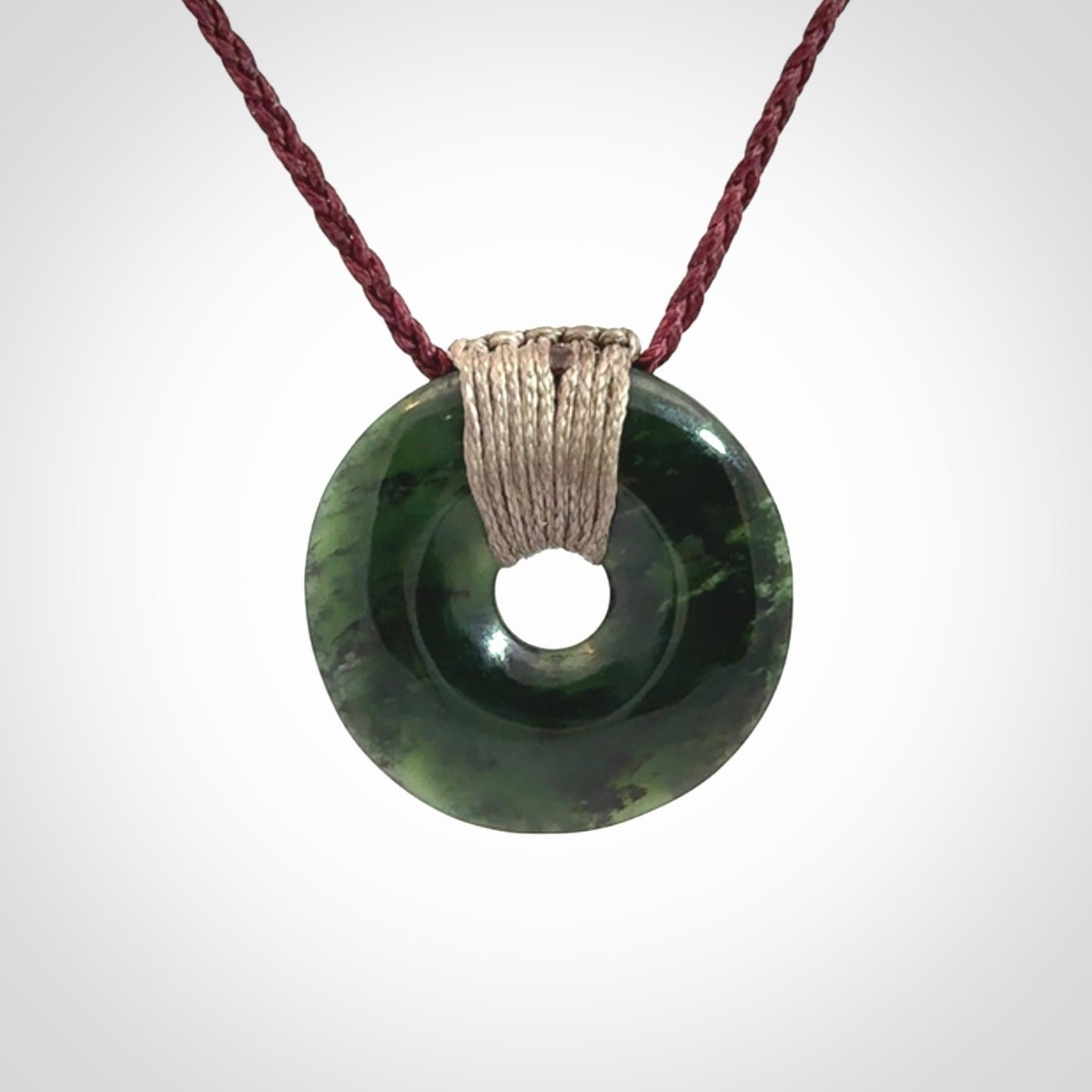 These are medium sized pendants - very finely carved. They are New Zealand Jade discs with a centre hole. It is suspended from a cord which is adjustable. These are beautiful pieces of expressive jade jewellery. Unique New Zealand made pendants for men and women. Perfect gifts for all.