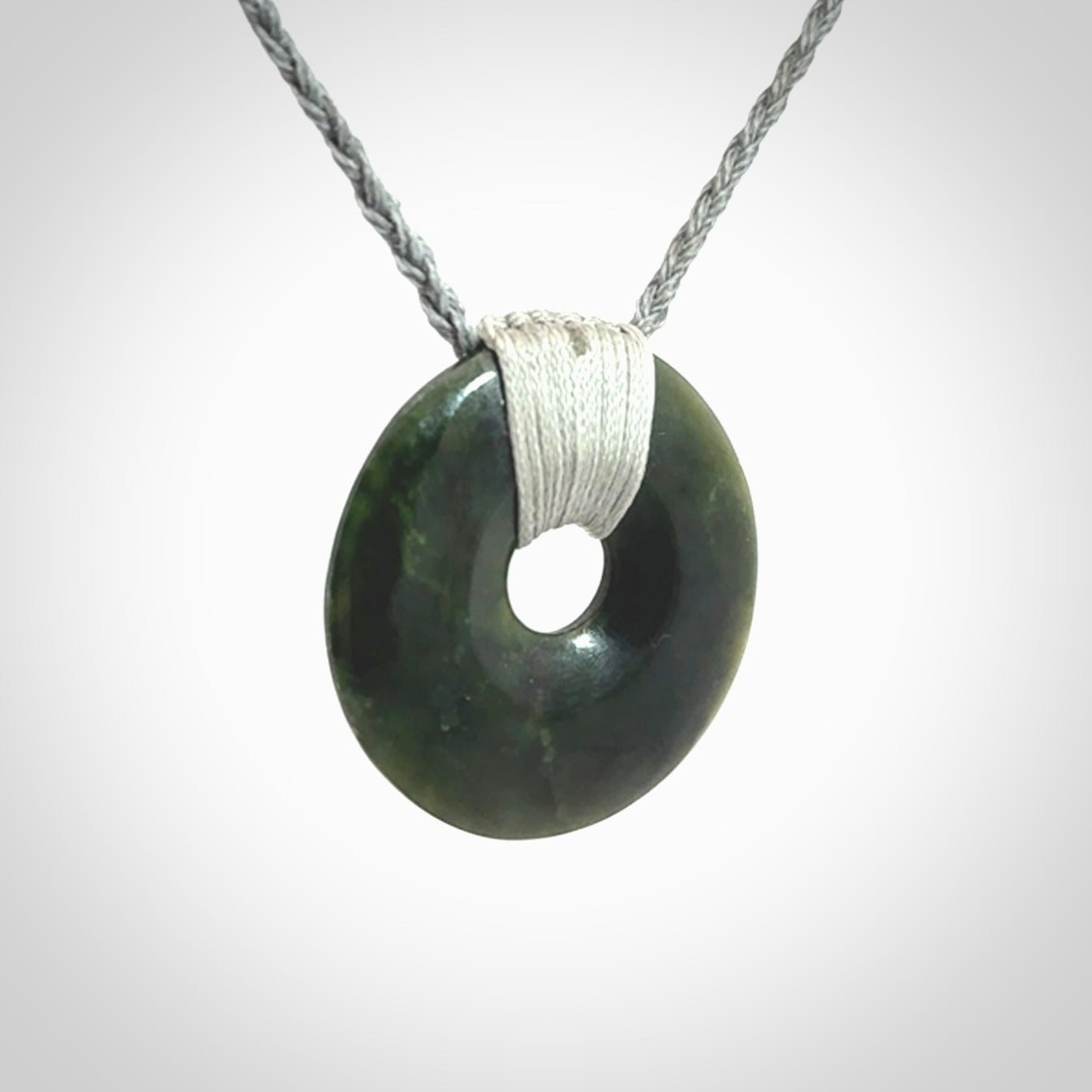 These are medium sized pendants - very finely carved. They are New Zealand Jade discs with a centre hole. It is suspended from a cord which is adjustable. These are beautiful pieces of expressive jade jewellery. Unique New Zealand made pendants for men and women. Perfect gifts for all.